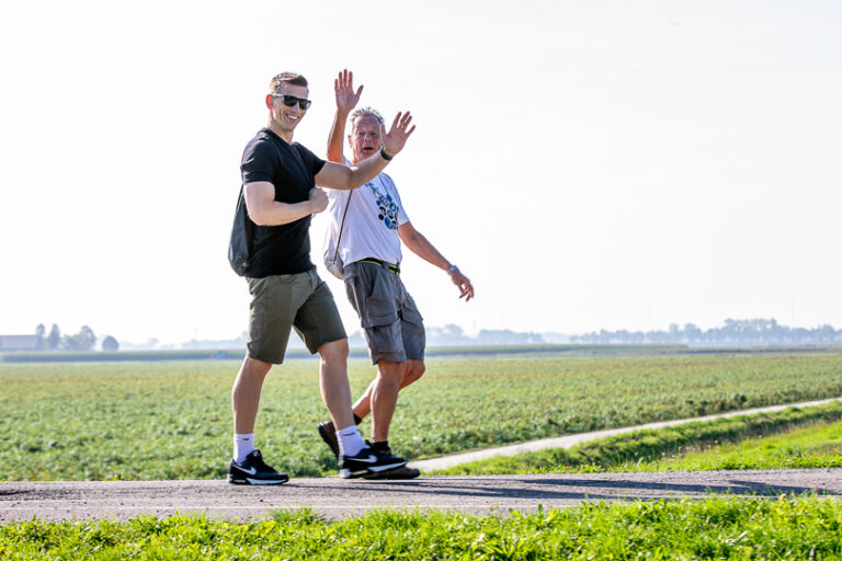 Twee wandelaars geven elkaar een high five op een polderweg